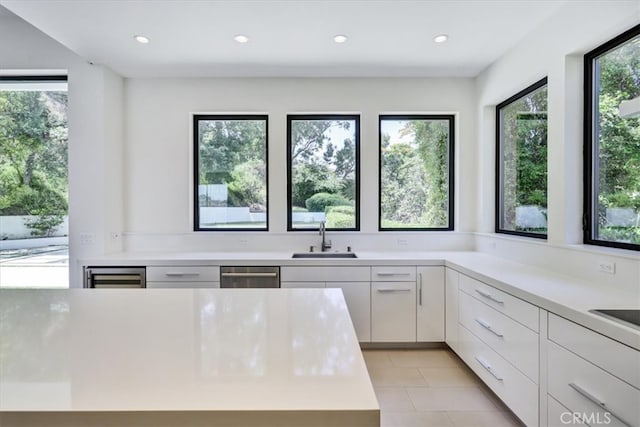 kitchen with light tile flooring, a healthy amount of sunlight, dishwasher, and sink