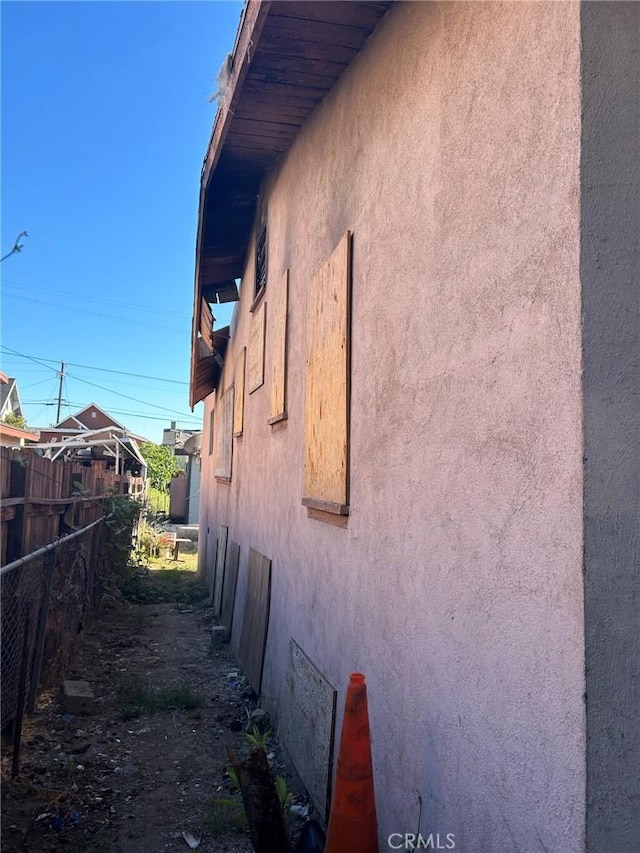 view of side of home with fence and stucco siding