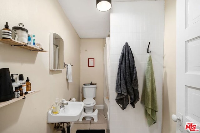 bathroom with toilet, sink, and tile patterned flooring