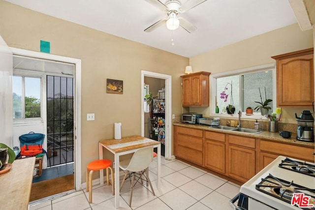 kitchen featuring ceiling fan, sink, light tile patterned flooring, and white range with gas stovetop