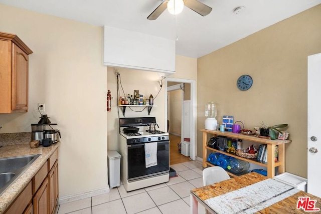 kitchen with ceiling fan, sink, light tile patterned floors, and white gas range oven