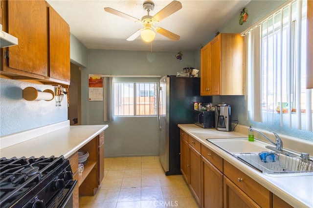 kitchen with ceiling fan, black range, sink, light tile floors, and exhaust hood