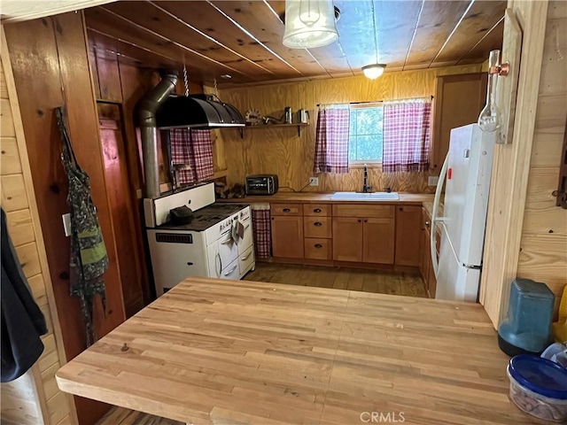 kitchen with sink, wood walls, pendant lighting, white appliances, and light wood-type flooring