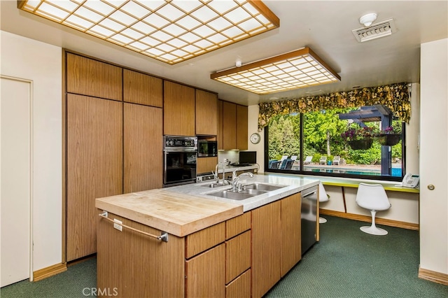 kitchen with sink, a kitchen island, stainless steel appliances, dark colored carpet, and built in desk