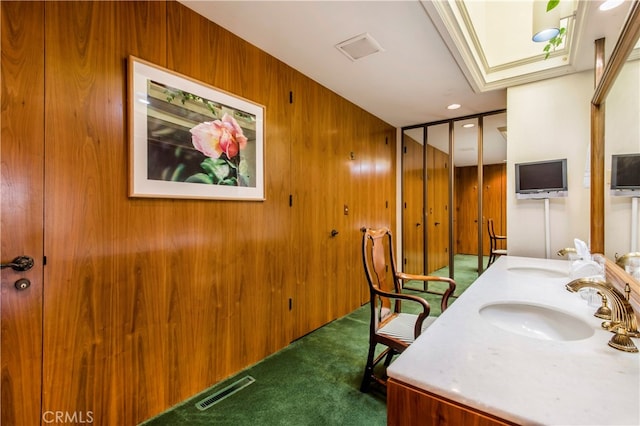 bathroom with wooden walls and dual bowl vanity