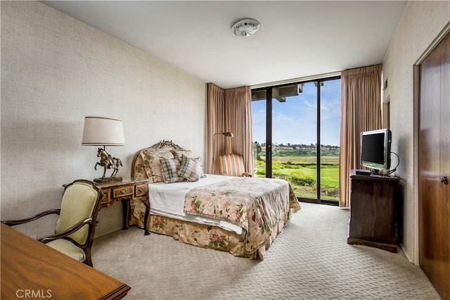 bedroom featuring light carpet, access to outside, and a wall of windows