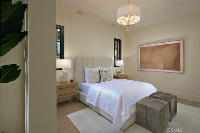 bedroom featuring an inviting chandelier and light wood-type flooring