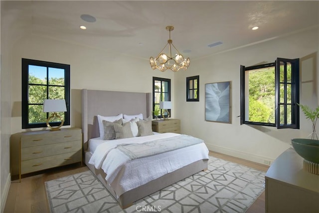 bedroom featuring an inviting chandelier and light hardwood / wood-style flooring