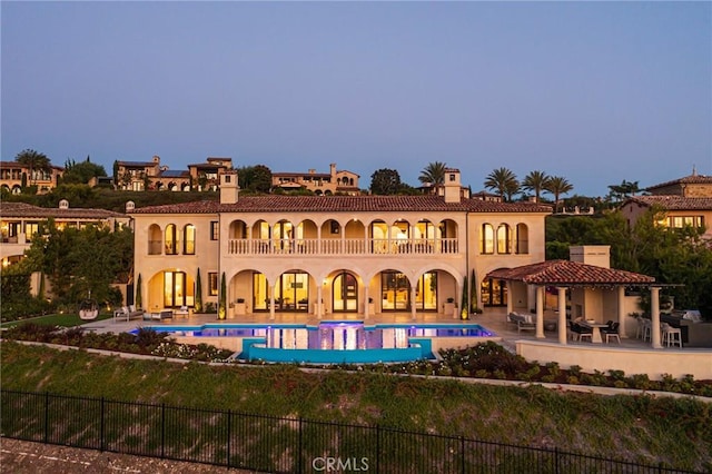 back house at dusk with a balcony and a patio area