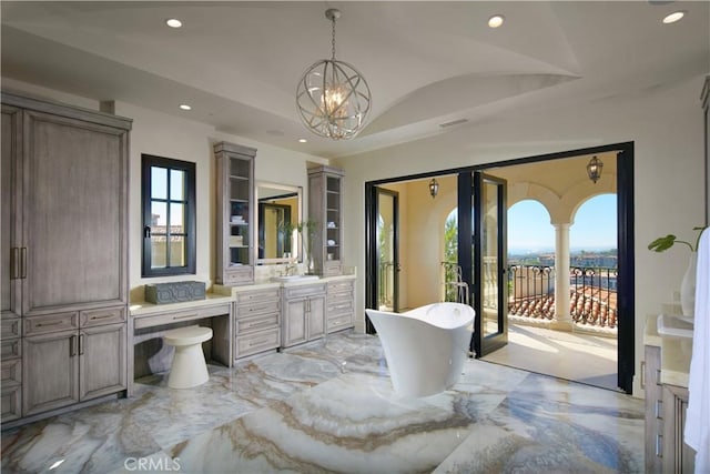 bathroom featuring a wealth of natural light, an inviting chandelier, lofted ceiling, and a bathing tub