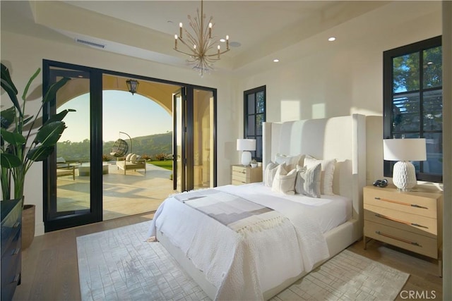 bedroom featuring access to outside, an inviting chandelier, french doors, and wood-type flooring