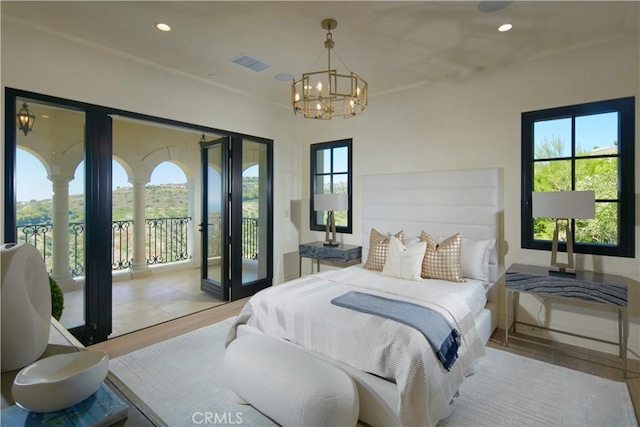 bedroom with light hardwood / wood-style flooring, access to outside, and an inviting chandelier