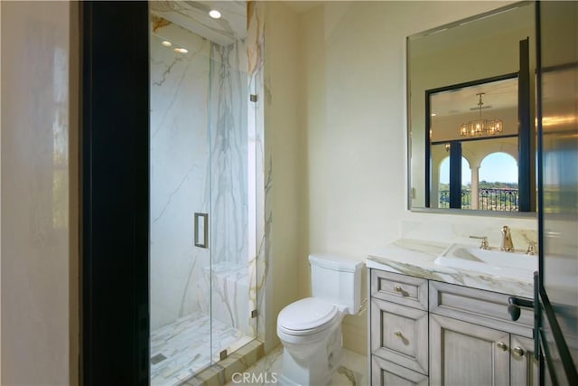 bathroom featuring toilet, a shower with door, vanity, and a notable chandelier