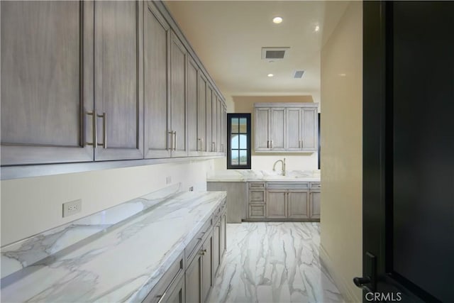 kitchen featuring sink and light stone countertops