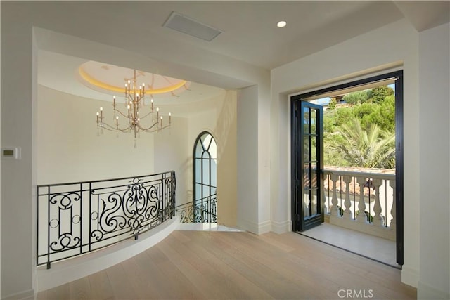 interior space with wood-type flooring, an inviting chandelier, and a tray ceiling