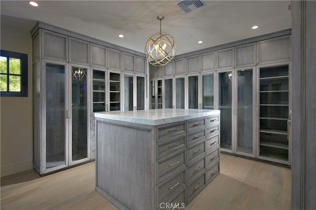 walk in closet featuring light hardwood / wood-style flooring and a chandelier