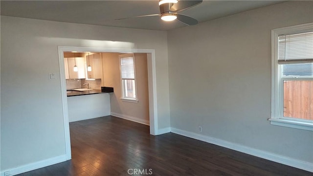 empty room with a sink, dark wood-style floors, baseboards, and ceiling fan