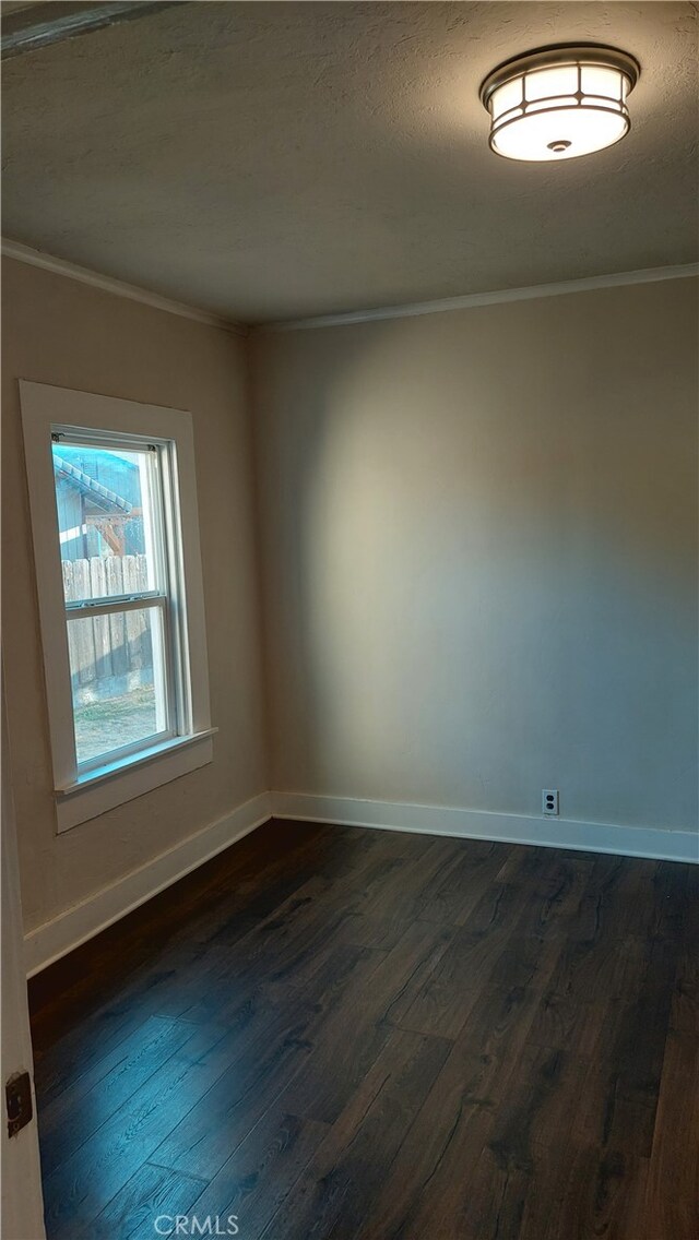 unfurnished room with ornamental molding and dark wood-type flooring