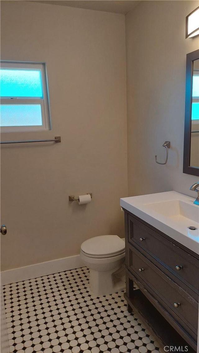 bathroom featuring baseboards, toilet, and vanity