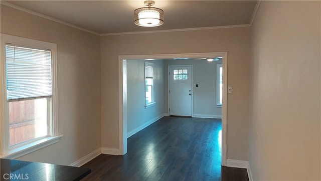 corridor with dark hardwood / wood-style floors, ornamental molding, and a healthy amount of sunlight