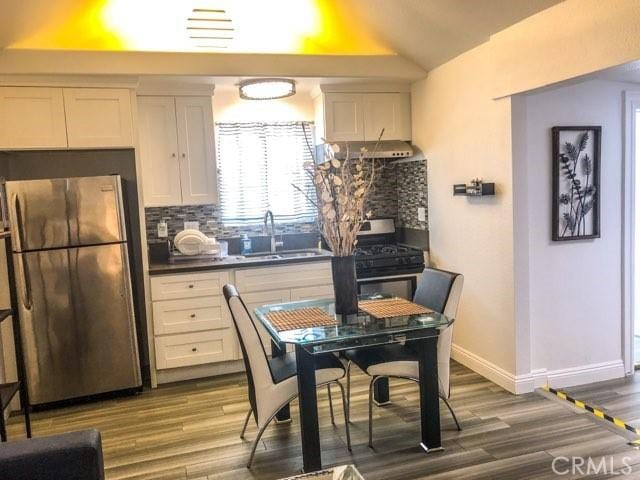 kitchen featuring sink, tasteful backsplash, white cabinetry, black range with gas cooktop, and stainless steel refrigerator