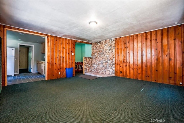 unfurnished room with wooden walls and dark colored carpet