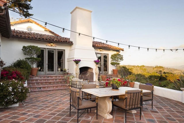 patio terrace at dusk with french doors and exterior fireplace