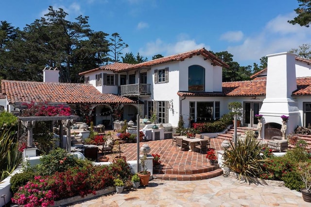 back of property featuring a fireplace, a patio, and a balcony