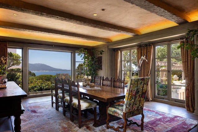 dining area with a mountain view, beam ceiling, plenty of natural light, and hardwood / wood-style floors