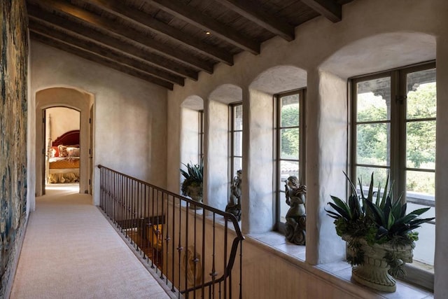 corridor with wooden ceiling, light colored carpet, and lofted ceiling with beams