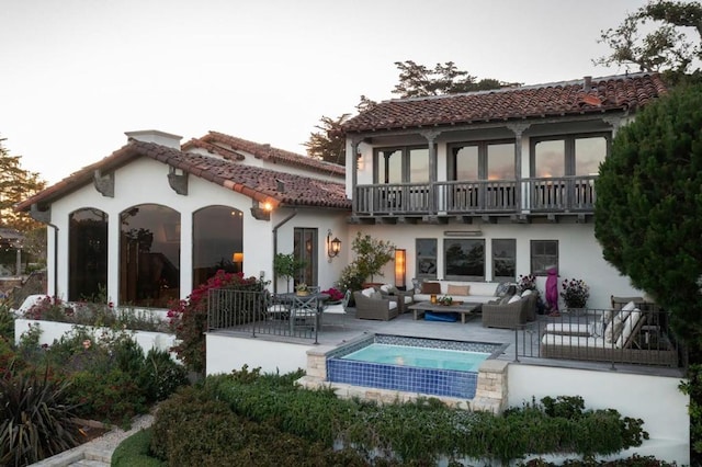 rear view of house with outdoor lounge area, a patio, and a balcony