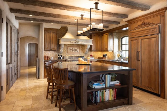 kitchen with decorative backsplash, sink, pendant lighting, beamed ceiling, and a kitchen island