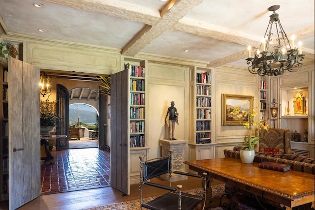 interior space featuring coffered ceiling, crown molding, wood-type flooring, beam ceiling, and a notable chandelier