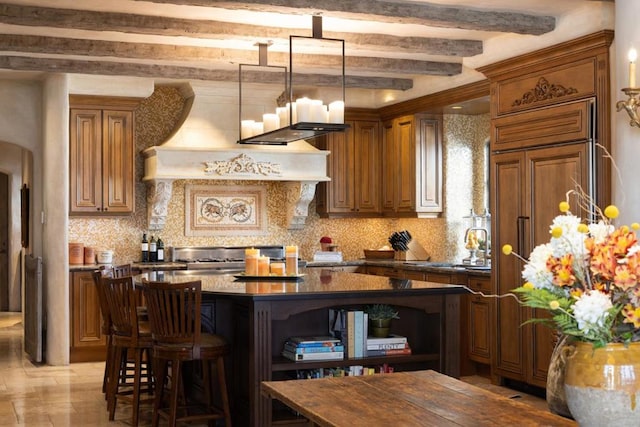 kitchen with beamed ceiling, tasteful backsplash, a kitchen island, and paneled built in refrigerator