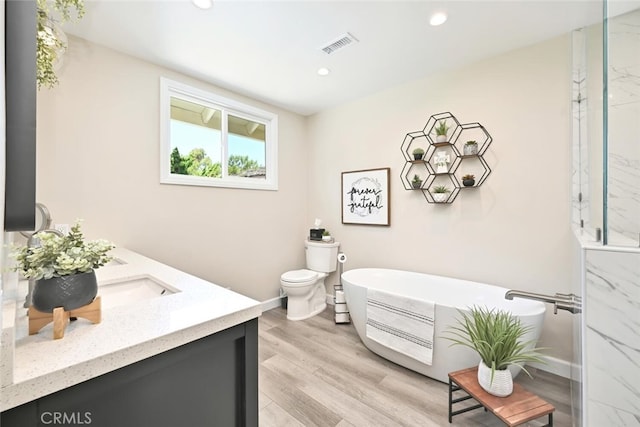 bathroom featuring a tub to relax in, hardwood / wood-style floors, vanity, and toilet