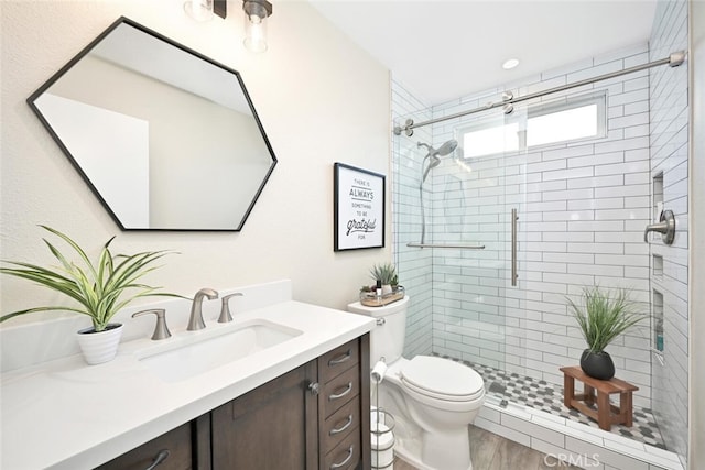 bathroom featuring hardwood / wood-style floors, vanity, toilet, and a shower with shower door