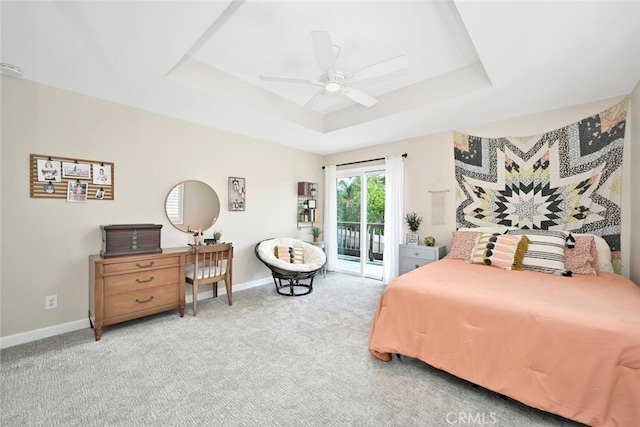 carpeted bedroom with access to outside, a raised ceiling, and ceiling fan