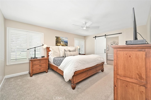 carpeted bedroom featuring a barn door and ceiling fan