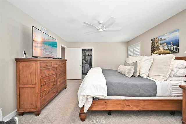 bedroom with ceiling fan, light colored carpet, a spacious closet, and a closet