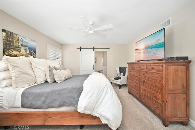 carpeted bedroom with a barn door and ceiling fan