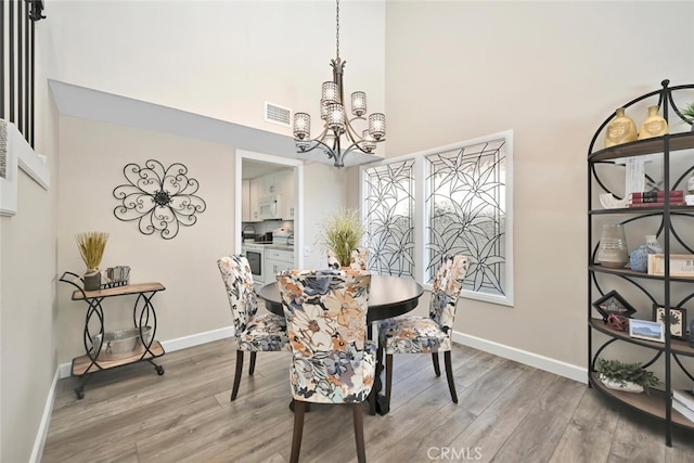 dining space featuring light hardwood / wood-style flooring, a high ceiling, and a chandelier