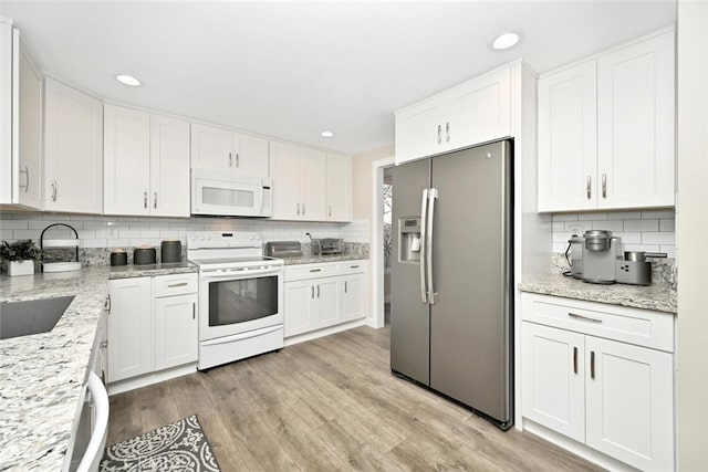 kitchen featuring white cabinets, backsplash, light hardwood / wood-style floors, and stainless steel appliances