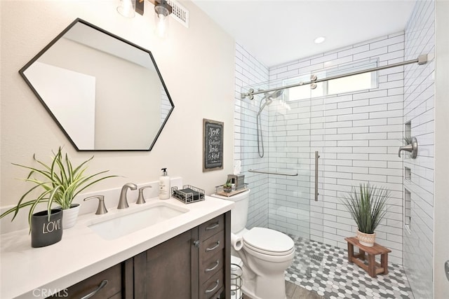 bathroom with vanity, toilet, and a shower with door