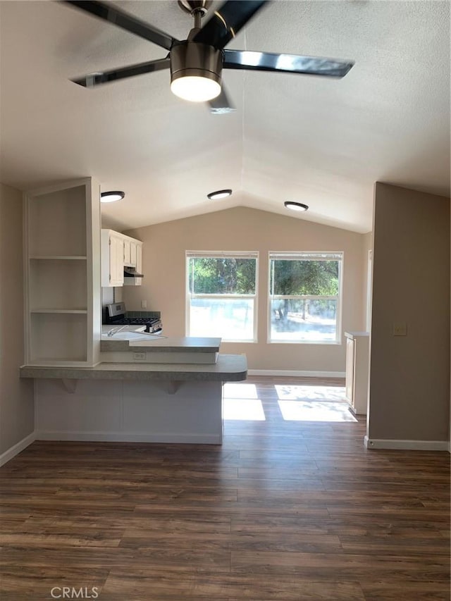 kitchen with white cabinetry, a kitchen bar, kitchen peninsula, ceiling fan, and dark wood-type flooring