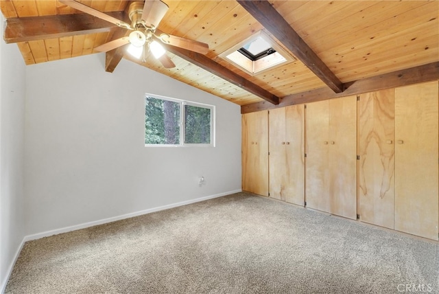 carpeted empty room featuring vaulted ceiling with skylight, ceiling fan, and wooden ceiling