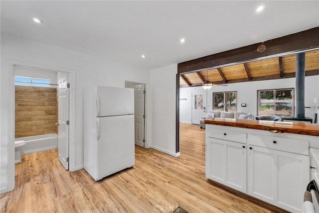 kitchen with ceiling fan, white fridge, lofted ceiling with beams, white cabinetry, and light wood-type flooring