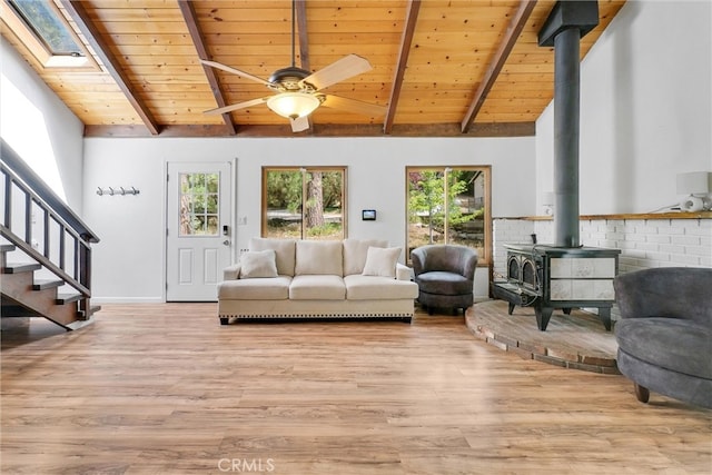 living room with ceiling fan, a wood stove, plenty of natural light, and light hardwood / wood-style floors