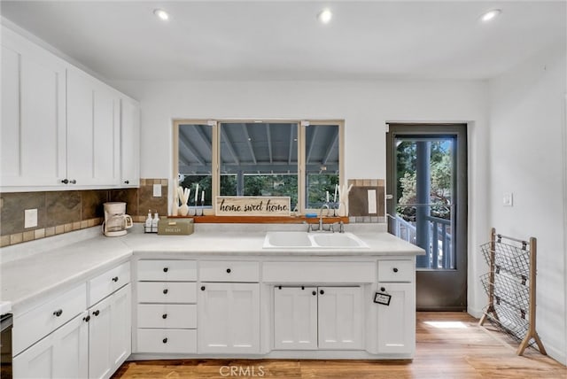 kitchen featuring white cabinets, backsplash, light hardwood / wood-style flooring, and sink