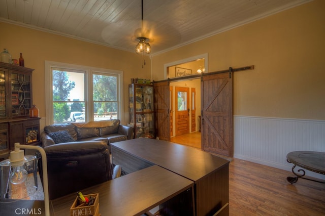 living room featuring a barn door, ornamental molding, and light hardwood / wood-style floors