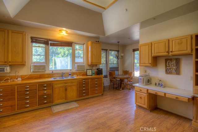 kitchen featuring sink, vaulted ceiling, and light hardwood / wood-style floors